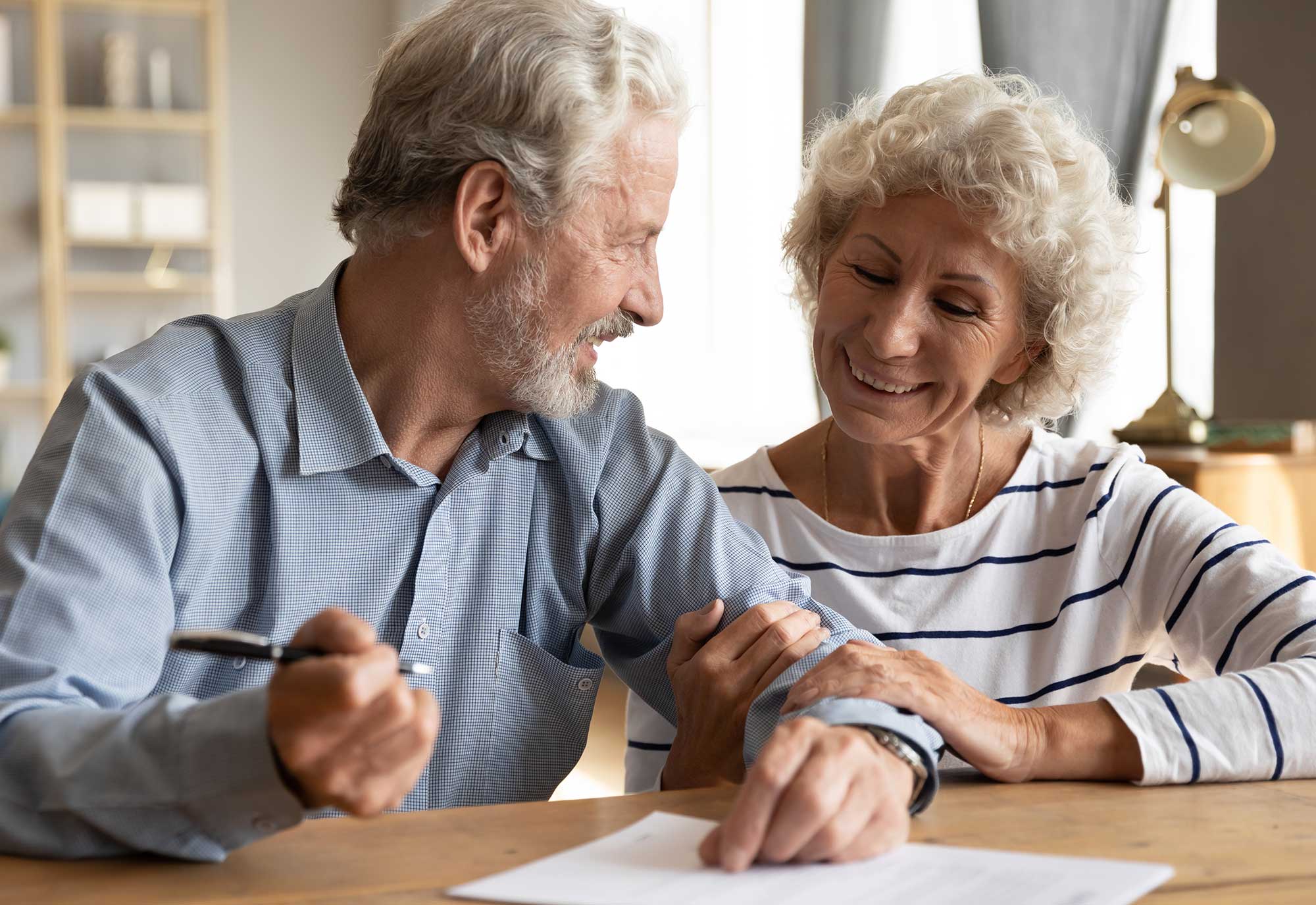 older couple sign forms at dining room table